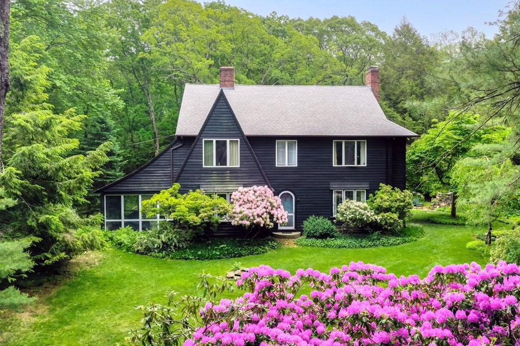 a front view of house and yard with beautiful flowers and green space