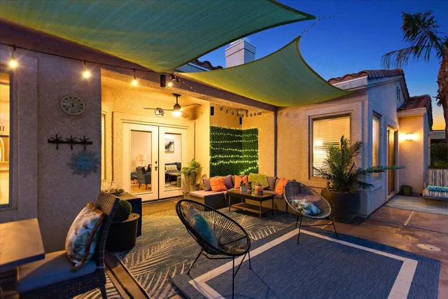 a view of a backyard with a table and chairs under an umbrella with palm trees