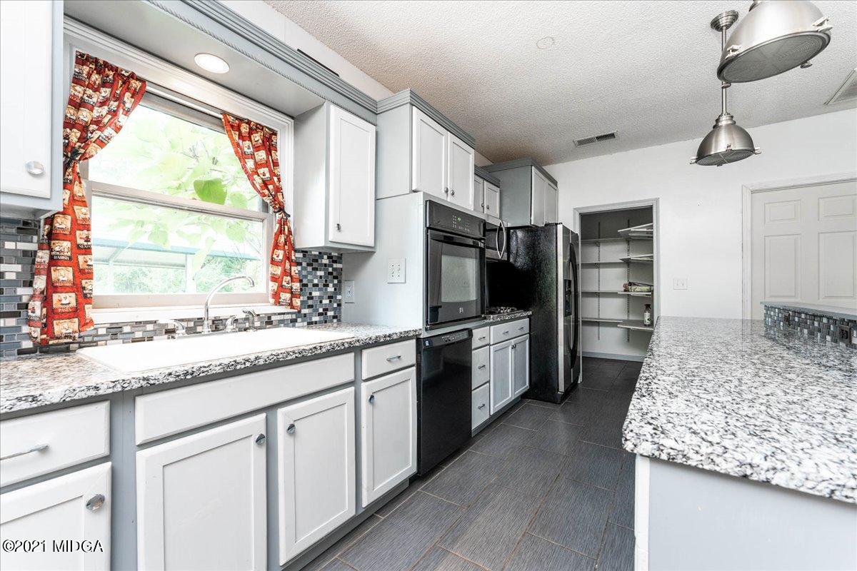 455 Lite-N-Tie Road Gray, GA 31032 - Photo 32 of 47 a kitchen with stainless steel appliances kitchen island granite countertop a refrigerator and a sink