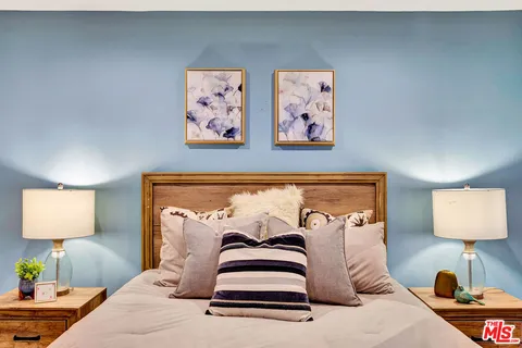 a bedroom with a bed and a lamp on dresser
