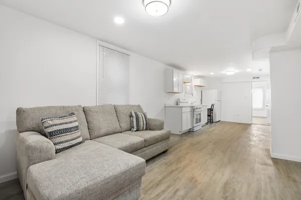 a living room with furniture white walls and kitchen view