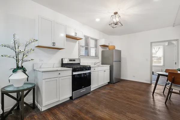 a kitchen with stainless steel appliances granite countertop a refrigerator a stove a sink dishwasher and white cabinets with wooden floor
