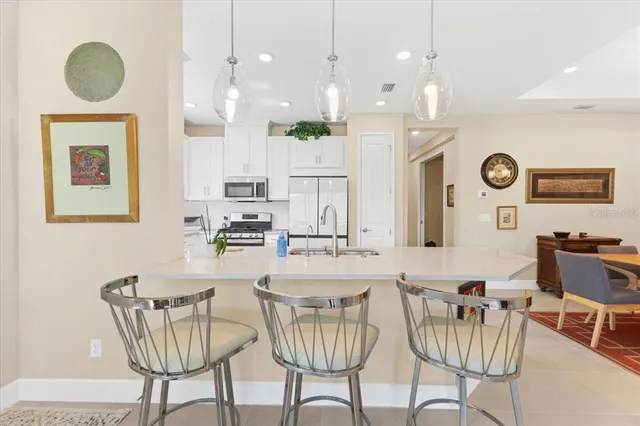 a kitchen with stainless steel appliances granite countertop a dining table chairs and a refrigerator