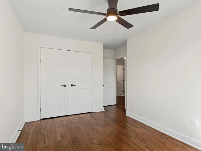 an empty room with wooden floor closet and fan