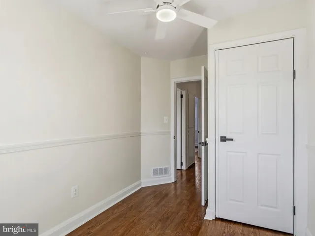 an empty room with wooden floor and a ceiling fan