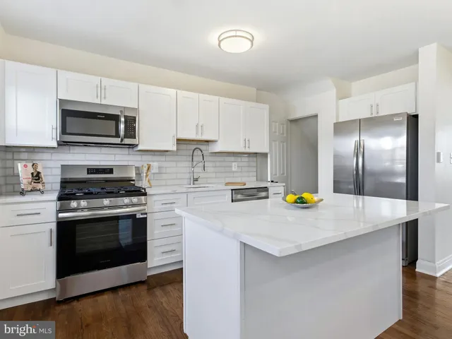 a kitchen with stainless steel appliances a stove a sink a microwave and white cabinets