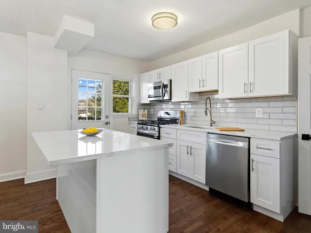 a kitchen with stainless steel appliances a stove a sink a refrigerator a center island and cabinets