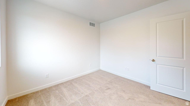 783 Pheasantbrook Drive, Unit 2A Centerville, UT 84014 - Photo 22 of 41 Room featuring neutral-toned walls, plush carpeting, a white paneled door with a brass-toned doorknob, white baseboards, and a visible air vent
