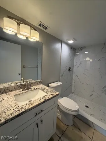 a bathroom with a granite countertop sink a toilet a mirror and shower