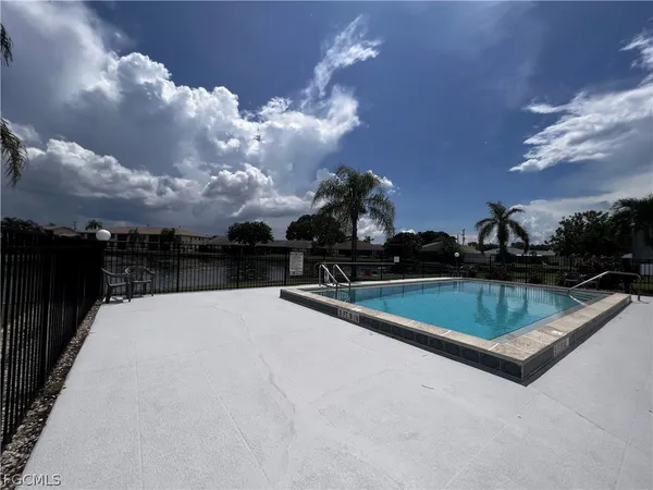 a view of swimming pool with outdoor seating and buildings in the background