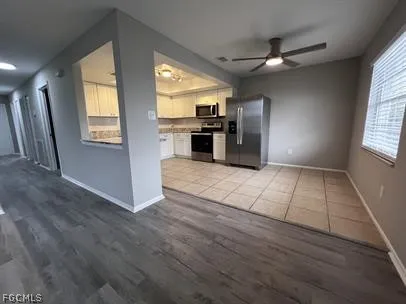 a view of a kitchen with wooden floor electronic appliances and windows