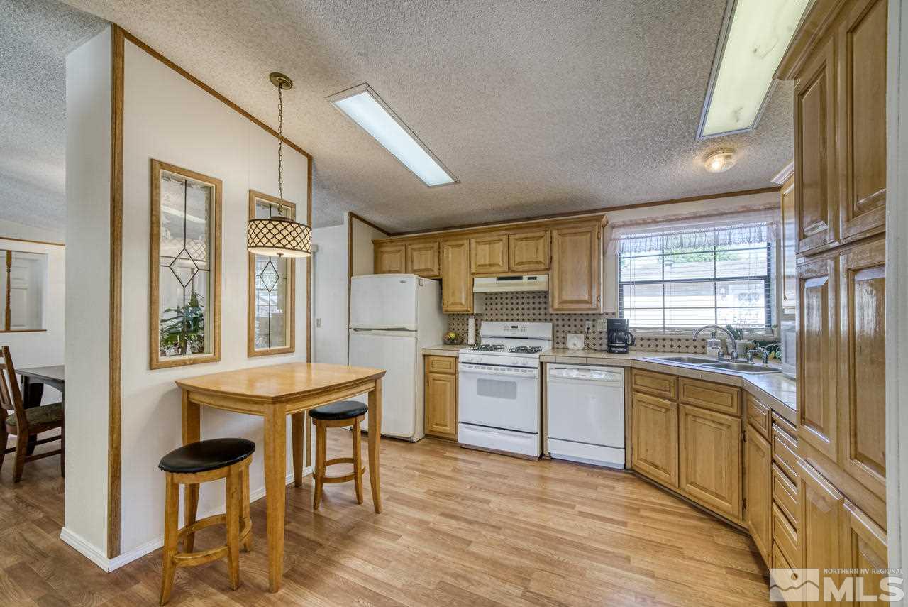 15030 Vega Street Reno, NV 89521 - Photo 11 of 29 a kitchen with stainless steel appliances granite countertop a stove top oven a sink dishwasher a dining table and chairs with wooden floor