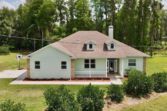 a aerial view of a house with swimming pool and next to trees