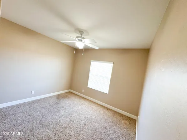 an empty room with a chandelier fan and windows