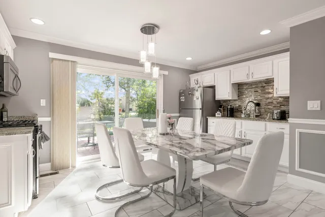 a dining room with furniture a large window and stainless steel appliances