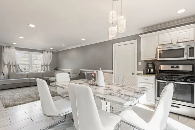 a kitchen with stainless steel appliances granite countertop a stove top oven a sink dishwasher a dining table and chairs with wooden floor