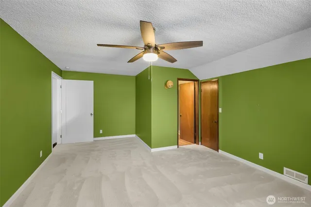 a view of a room with a large window and ceiling fan