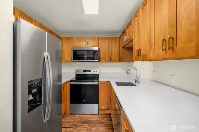 a kitchen with stainless steel appliances a refrigerator a sink a stove and cabinets