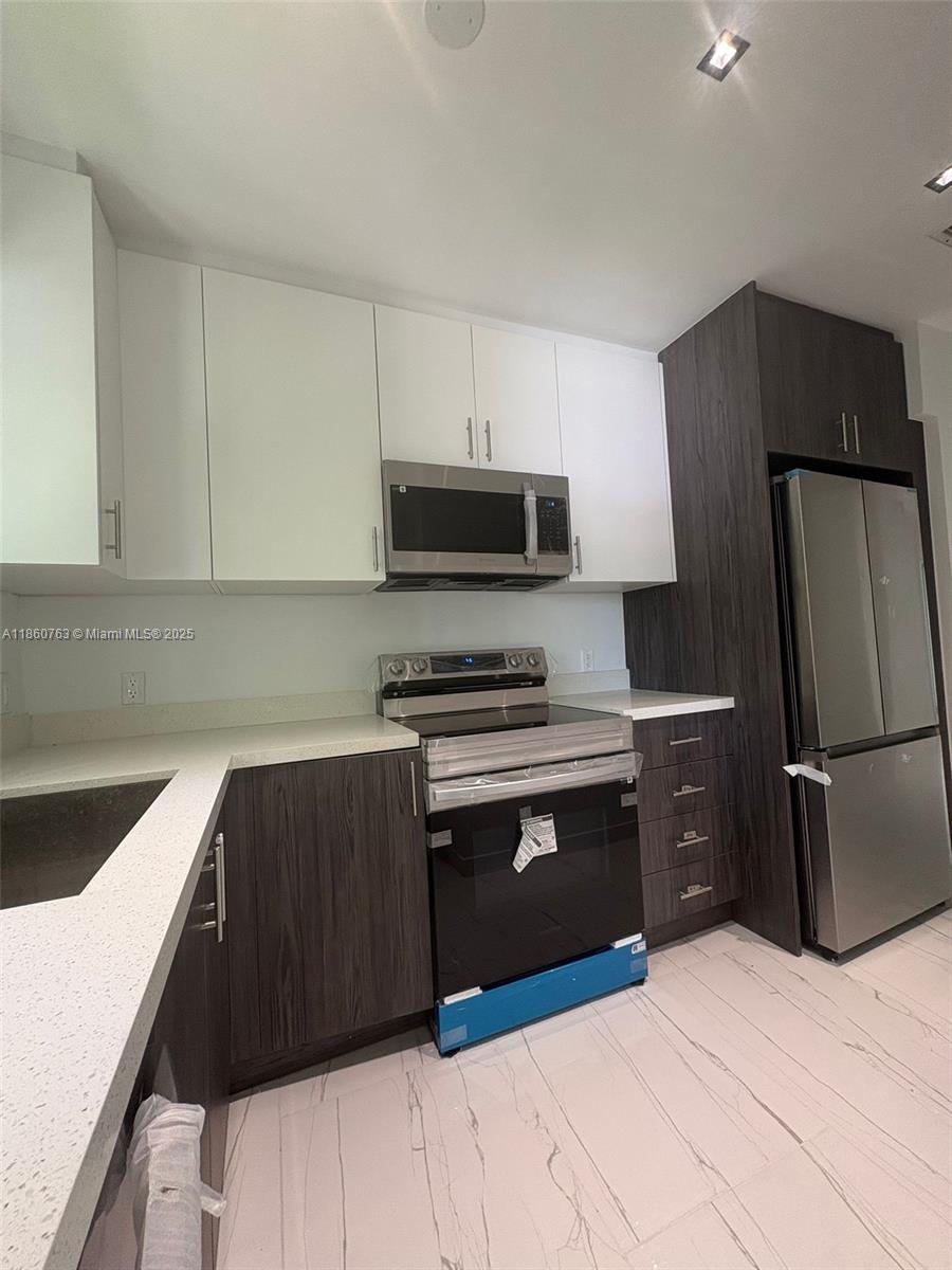 a kitchen with stainless steel appliances a refrigerator stove and microwave