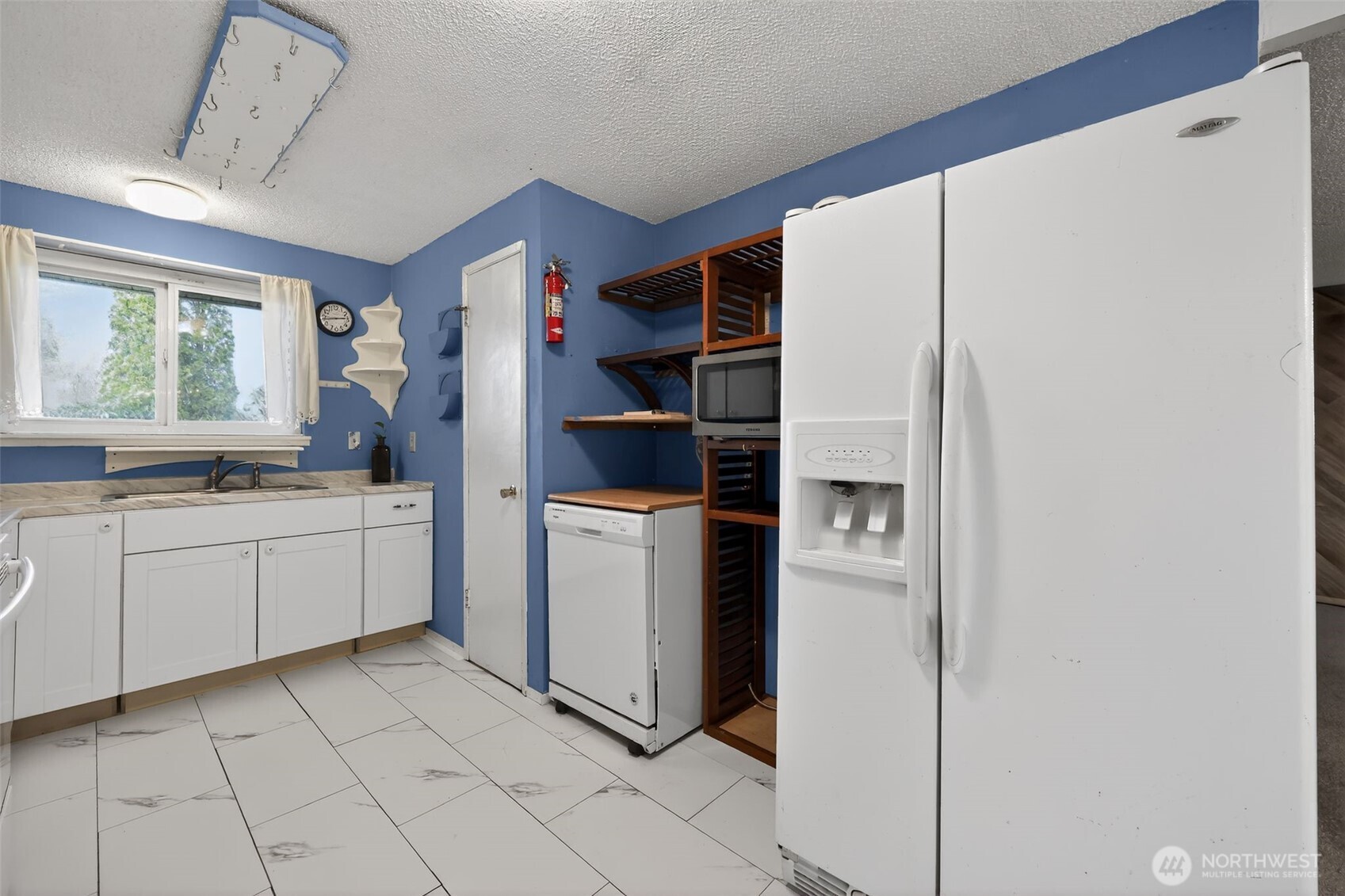 1010 Coolidge Road Aberdeen, WA 98520 - Photo 10 of 22 a kitchen with a refrigerator and white cabinets