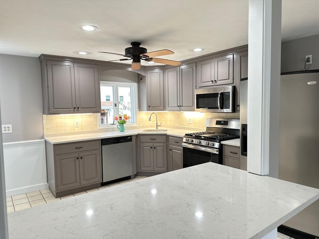 a kitchen with kitchen island granite countertop a stove top oven microwave and cabinets