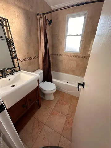 an empty room with a chandelier fan and a window