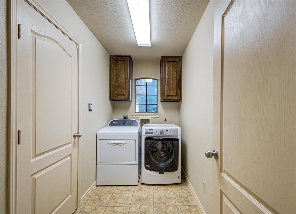 2105 Ridgewood Drive Bridgeport, TX 76426 - Photo 27 of 27 Dedicated utility space featuring tiled flooring, built-in cabinetry, an arched window, and overhead lighting