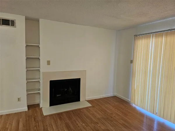 a view of an empty room with a fireplace and a window