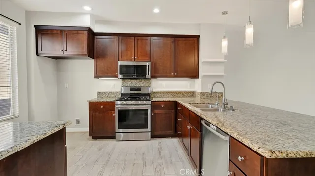 a kitchen with stainless steel appliances granite countertop a sink stove and refrigerator