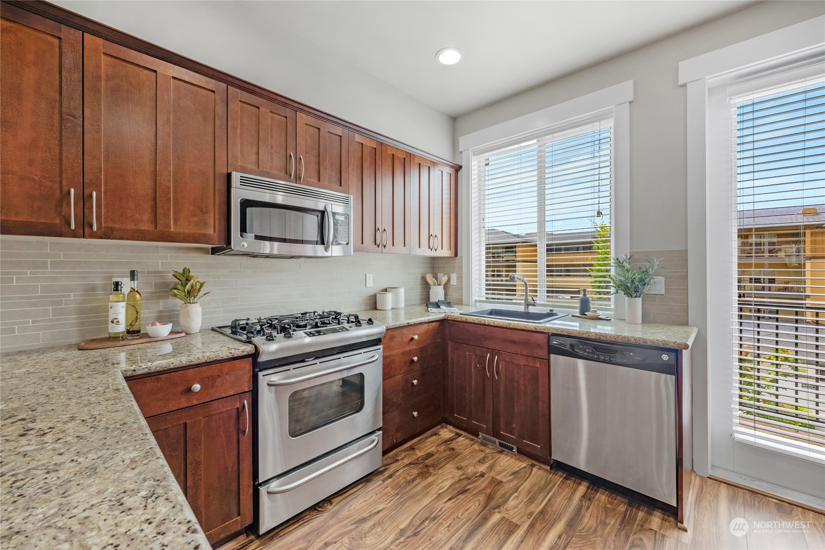 2115 201st Place Southeast, Unit D2 Bothell, WA 98012 - Photo 13 of 31 a kitchen with stainless steel appliances granite countertop wooden cabinets a stove a sink and a window