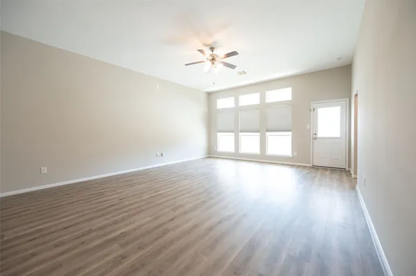 a view of an empty room with wooden floor and a window