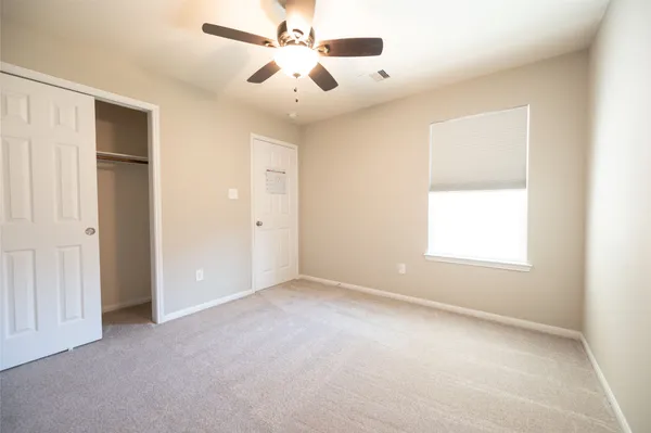 an empty room with a window and a fan