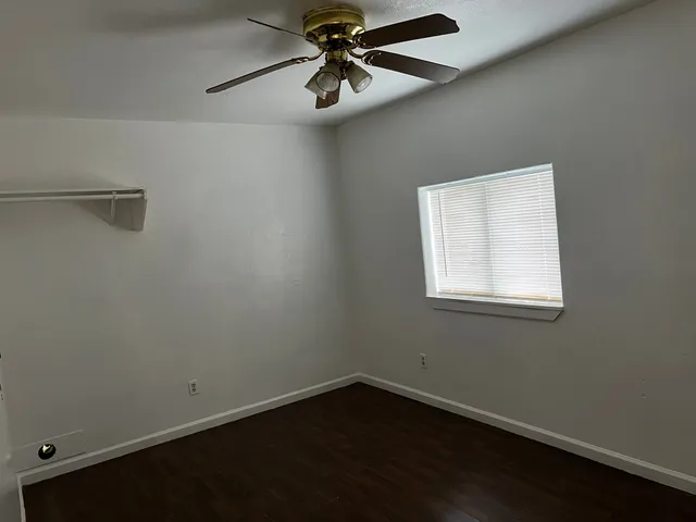 an empty room with a window and a fan
