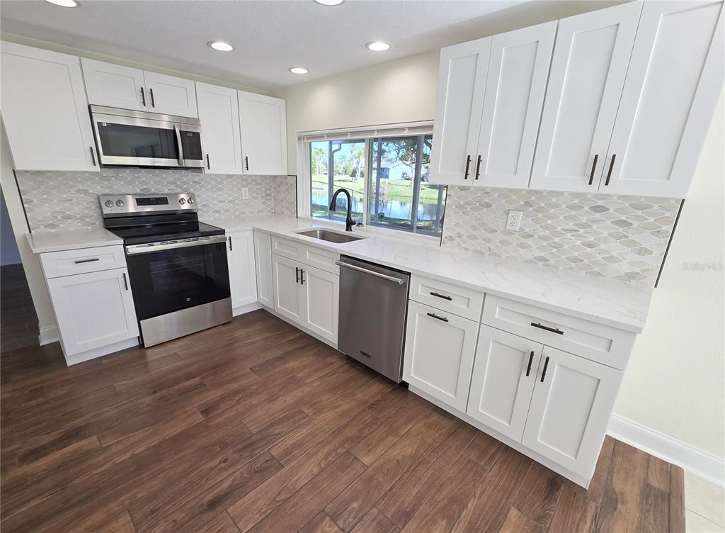 3604 Delta Place Holiday, FL 34691 - Photo 4 of 41 a kitchen with granite countertop white cabinets and white appliances