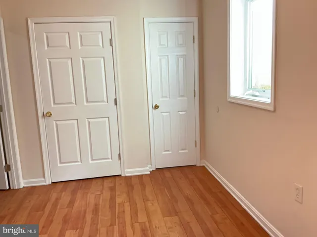 an empty room with wooden floor and closet area