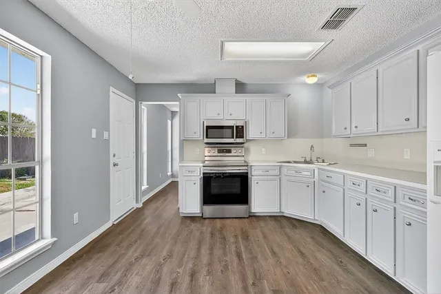 a kitchen with granite countertop white cabinets and stainless steel appliances