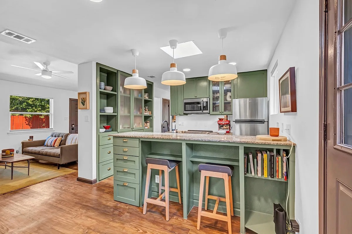 2307 Teri Road Austin, TX 78744 - Photo 7 of 28 Kitchen featuring green cabinets, a kitchen breakfast bar, glass insert cabinets, stainless steel appliances, and a ceiling fan