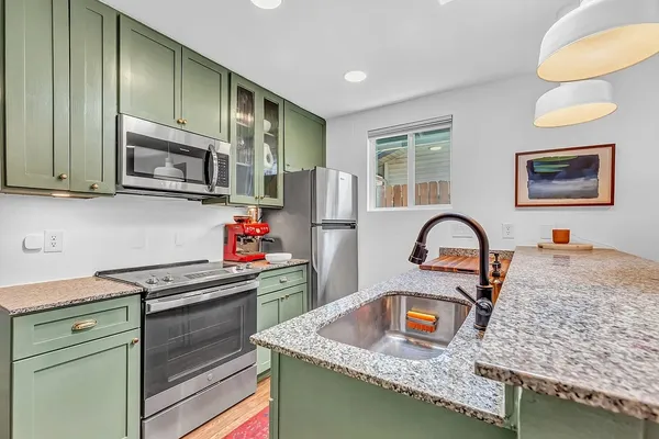 a kitchen with stainless steel appliances granite countertop a stove a sink and a microwave