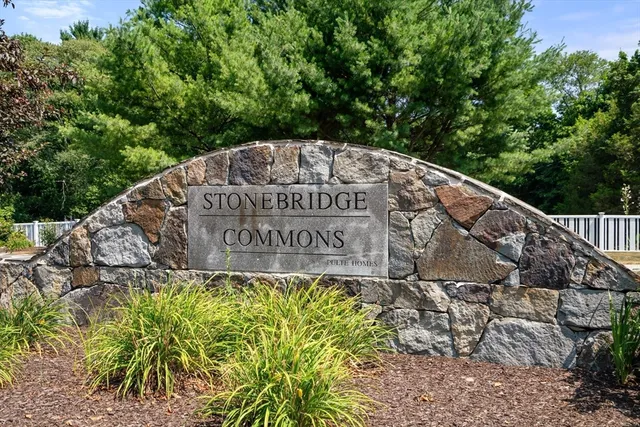 a sign of golf club on a stone wall under a tree