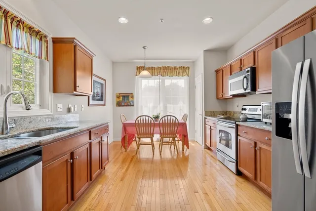 a kitchen with stainless steel appliances granite countertop wooden floors a stove a sink dishwasher and cabinets with wooden floor