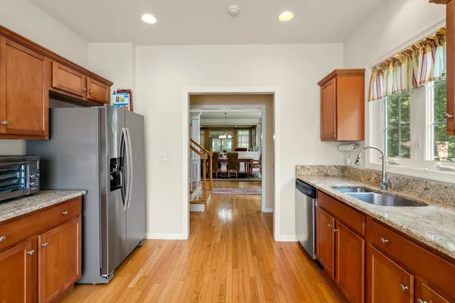 a kitchen with stainless steel appliances granite countertop a refrigerator a sink dishwasher a stove and white countertops with wooden floor