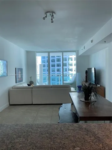 a hallway view with furniture and a flat screen tv