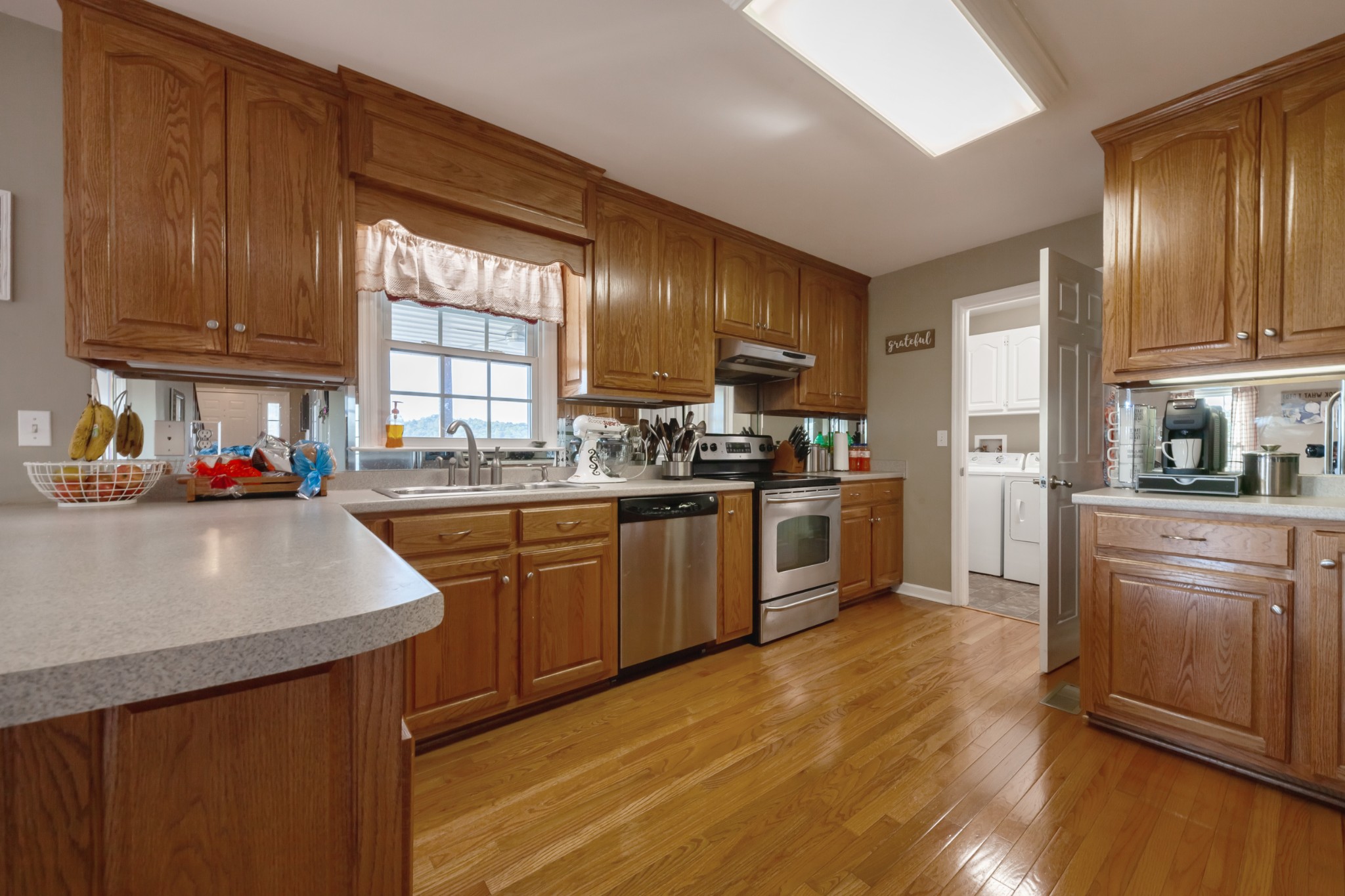 7055 Buford Station Road Lynnville, TN 38472 - Photo 15 of 34 a kitchen with granite countertop wooden floors stainless steel appliances a sink and a window