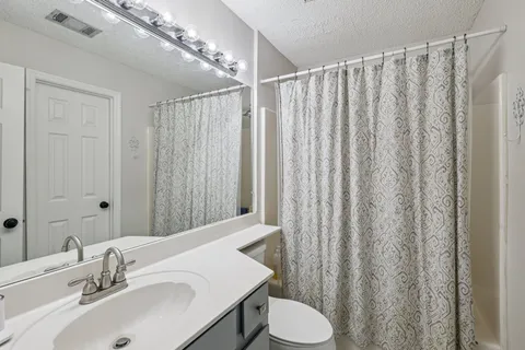 a bathroom with a sink a toilet and shower curtain