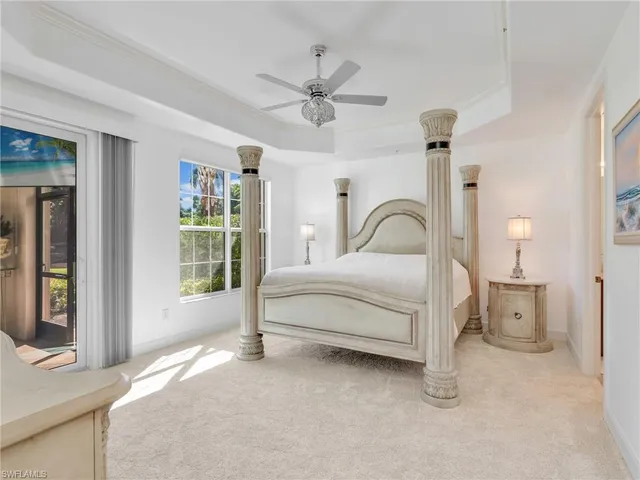 a bedroom with a bed next to a window with a chandelier