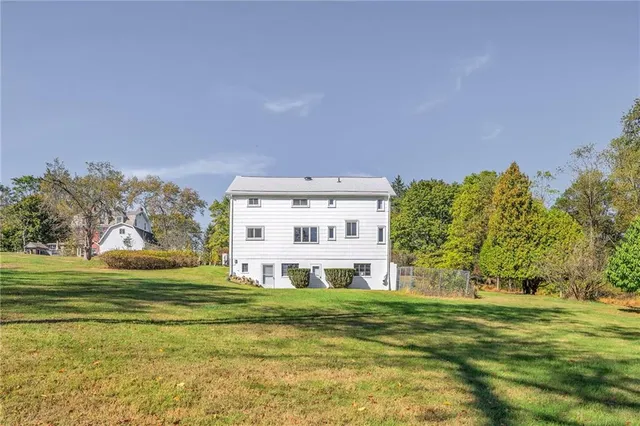 a view of a house with a big yard and large trees