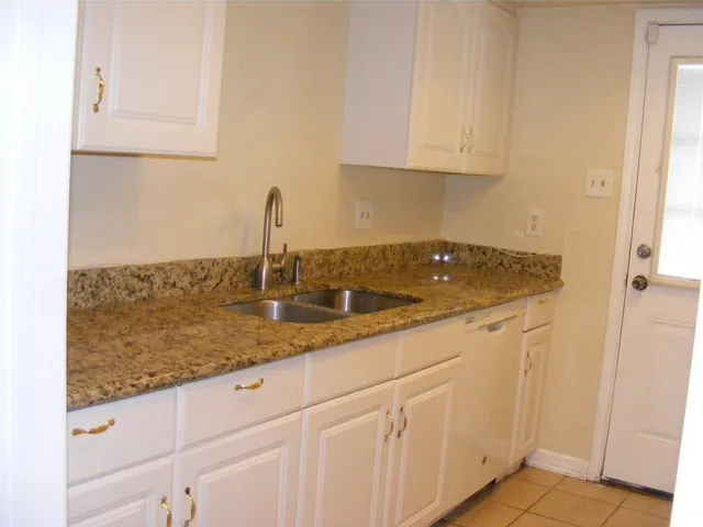 a kitchen with granite countertop white cabinets and a sink