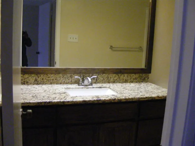 a bathroom with a granite countertop sink and a mirror