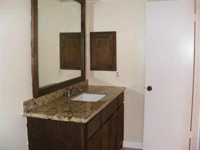 a bathroom with a granite countertop sink and a mirror