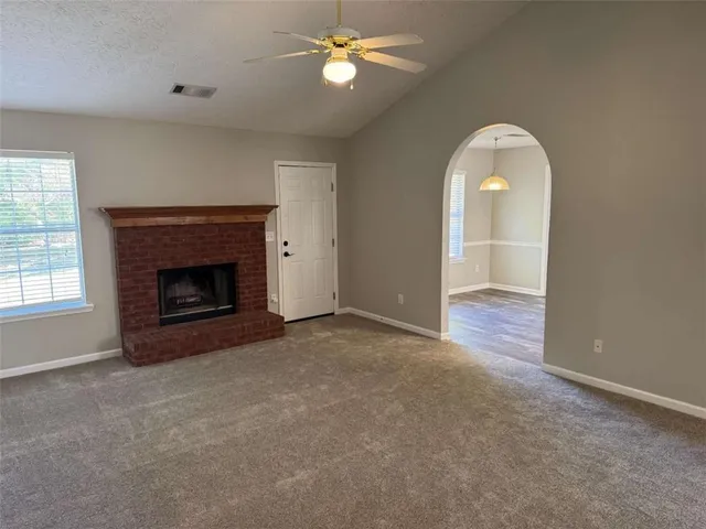 an empty room with windows and fireplace